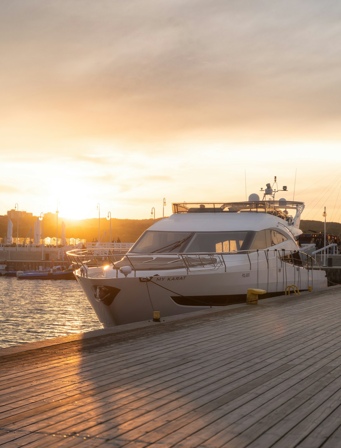 A white motor yacht is moored at a wooden pier.